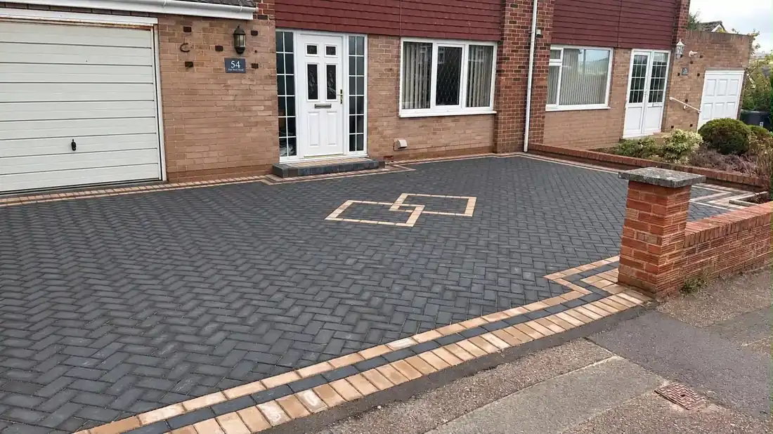 Charcoal block-paved front drive with a geometric buff inset